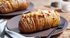 a baked potato with cheese and bacon on it sitting on a plate next to a fork