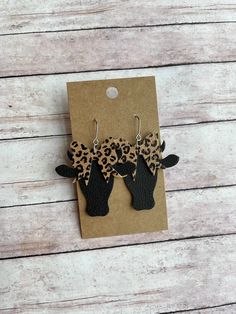 the leopard print earrings are on display in front of a brown card with an animal print bow