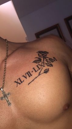 a close up of a man's chest with a cross and rose tattoo on it