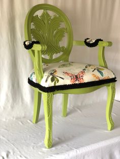 a green chair with a flowered seat cushion and black piping on the back