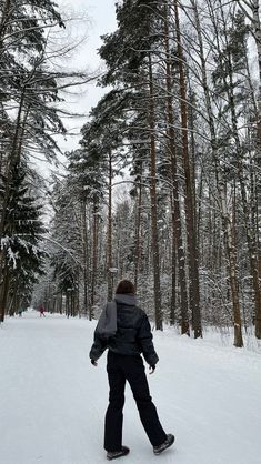 a person standing in the snow near some trees