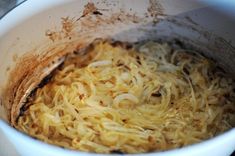 a white bowl filled with noodles on top of a stove burner covered in grease