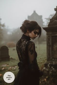 a woman standing in front of a cemetery on a foggy day with her eyes closed