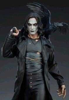 the crow figure is dressed in black leather and has his hands on his head, while he