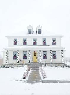 a large white house with christmas wreaths on the front door