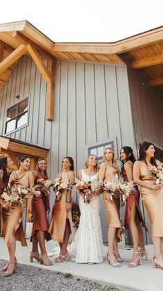 a group of women standing next to each other in front of a building holding bouquets