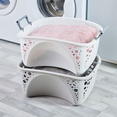 two laundry baskets stacked on top of each other in front of a washer and dryer