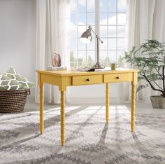 a yellow desk with two drawers and a lamp on it in front of a window