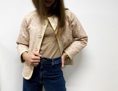 a woman standing in front of a white wall with her hands on her hips and looking down