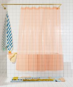 the shower curtain is pink and blue with yellow accents on it, along with other bathroom accessories