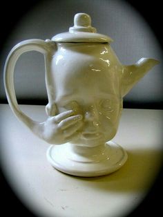 a white ceramic teapot with a face on it