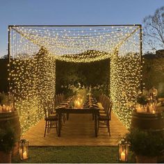 an outdoor dining area is lit up with fairy lights and candles for a festive effect