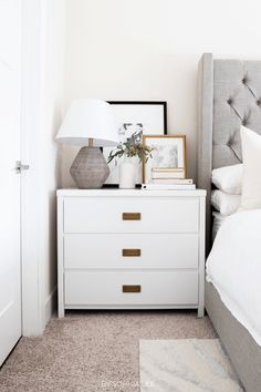 a bedroom with a bed, nightstand and pictures on the side table in front of it