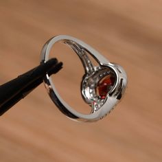 It is a natural garnet ring. The main stone is 6mm*8mm oval cut, weight about 1.73 carats. The basic metal is sterling silver and plated with rhodium. To change the metal to a solid gold (white/rose) or platinum is also available, please ask for a quotation if you want. You can also go to my shop Home for more elegant rings: https://www.etsy.com/shop/godjewelry?ref=hdr_shop_menu More garnet rings: https://www.etsy.com/shop/godjewelry?ref=seller-platform-mcnav&section_id=20709242 Customizatio Classic Garnet Jewelry With Halo Setting, Oval Ruby Birthstone Ring With Halo Setting, Garnet Halo Setting Rings In Fine Jewelry, Elegant Garnet Rings With Halo Setting, Round Garnet Ring With Halo Setting, Round Garnet Jewelry With Halo Setting, Elegant Oval Garnet Birthstone Ring, Oval Garnet Jewelry With Halo Setting, Silver Colored Ruby Ring With Halo