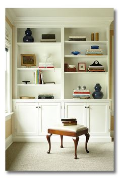 a living room with white bookcases filled with books and vases on top of them