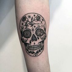 a black and white skull tattoo on the arm