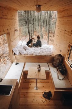 two dogs sitting on top of a bed in a room with wooden walls and flooring