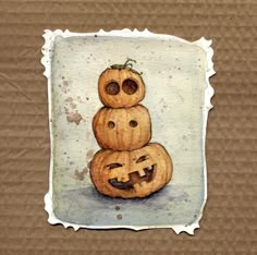 three carved pumpkins sitting on top of each other in front of a brown background