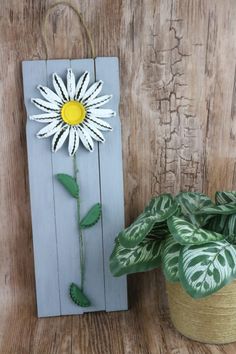 a wooden sign with a flower on it next to a potted plant