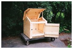 a small wooden box on wheels in front of some trees