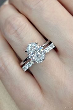 a woman's hand holding an engagement ring with two stones on the band and one stone in the middle