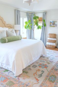 a white bed sitting in a bedroom next to a window with blue drapes on it