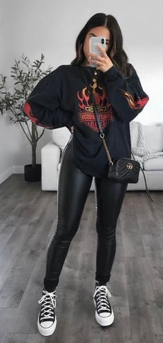 a woman taking a selfie in her living room wearing black leather leggings