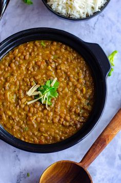 two bowls filled with beans and rice next to wooden spoons