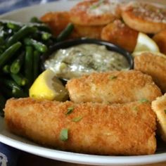 a white plate topped with fried fish and vegetables