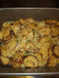 a metal pan filled with potatoes covered in parmesan cheese