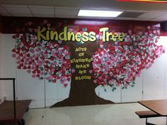 an office with a large tree painted on the wall and tables in front of it