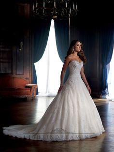 a woman in a white wedding dress posing for a photo with a chandelier