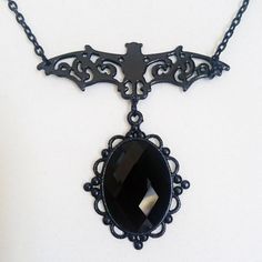 A black filigree ornate bat with a beautiful faceted purple or black glass cabochon gem!   Bat charm measures 5.5 x 2cm  (approx)  Cabochon measures 4 x 3 cm with gem measuring 1.8 x 2.5 cm Chain circumference is adjustable from 40 to 48 cm. Black Vampire Pendant Jewelry, Black Vampire Style Pendant Jewelry, Black Witchy Jewelry For Halloween, Witchy Black Jewelry For Halloween, Witchy Black Halloween Jewelry, Black Vampire Jewelry For Halloween, Vampire Style Black Jewelry For Halloween, Elegant Metal Necklaces For Halloween, Black Pendant Jewelry For Halloween