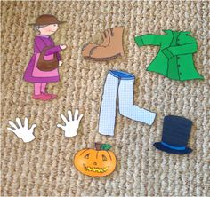 paper cutouts of clothes, hats and hands on the floor next to an orange pumpkin