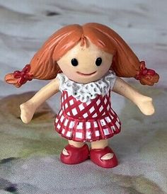 a small doll with red hair wearing a dress