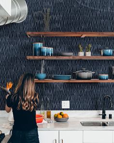 a woman standing in a kitchen preparing food on top of a counter next to a sink