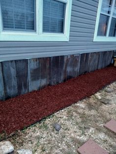 the side of a house with red mulch on the ground