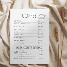 a menu with coffee drinks on it sitting on top of a bed covered in linen