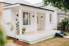 a small white house sitting on top of a grass covered yard next to a tree