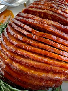 slices of bacon on a plate with rosemary sprigs and spoons in the background