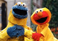 two sesame street characters dressed in yellow raincoats and holding hands with each other