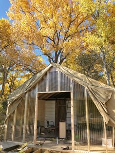 an outhouse with a covered patio and trees in the background