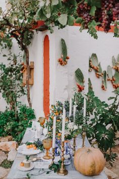 a table with candles, plates and pumpkins on it in front of a wall