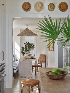 a dining room table that has some fruit on it and two hats hanging from the ceiling