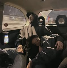 two people sleeping in the back seat of a car