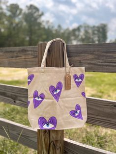 a bag with purple hearts on it hanging from a wooden fence