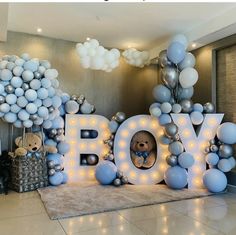 a teddy bear is sitting in the center of balloons that spell out the word boy