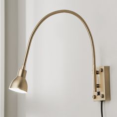 a light that is on the side of a white wall next to a black cord