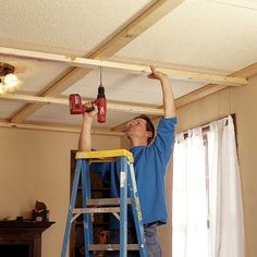 a man on a ladder working on a ceiling