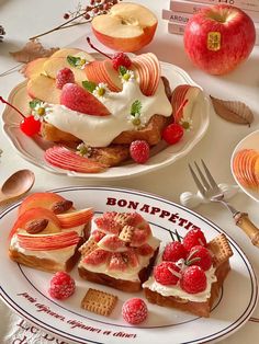 two plates topped with desserts on top of a table next to apples and other fruit